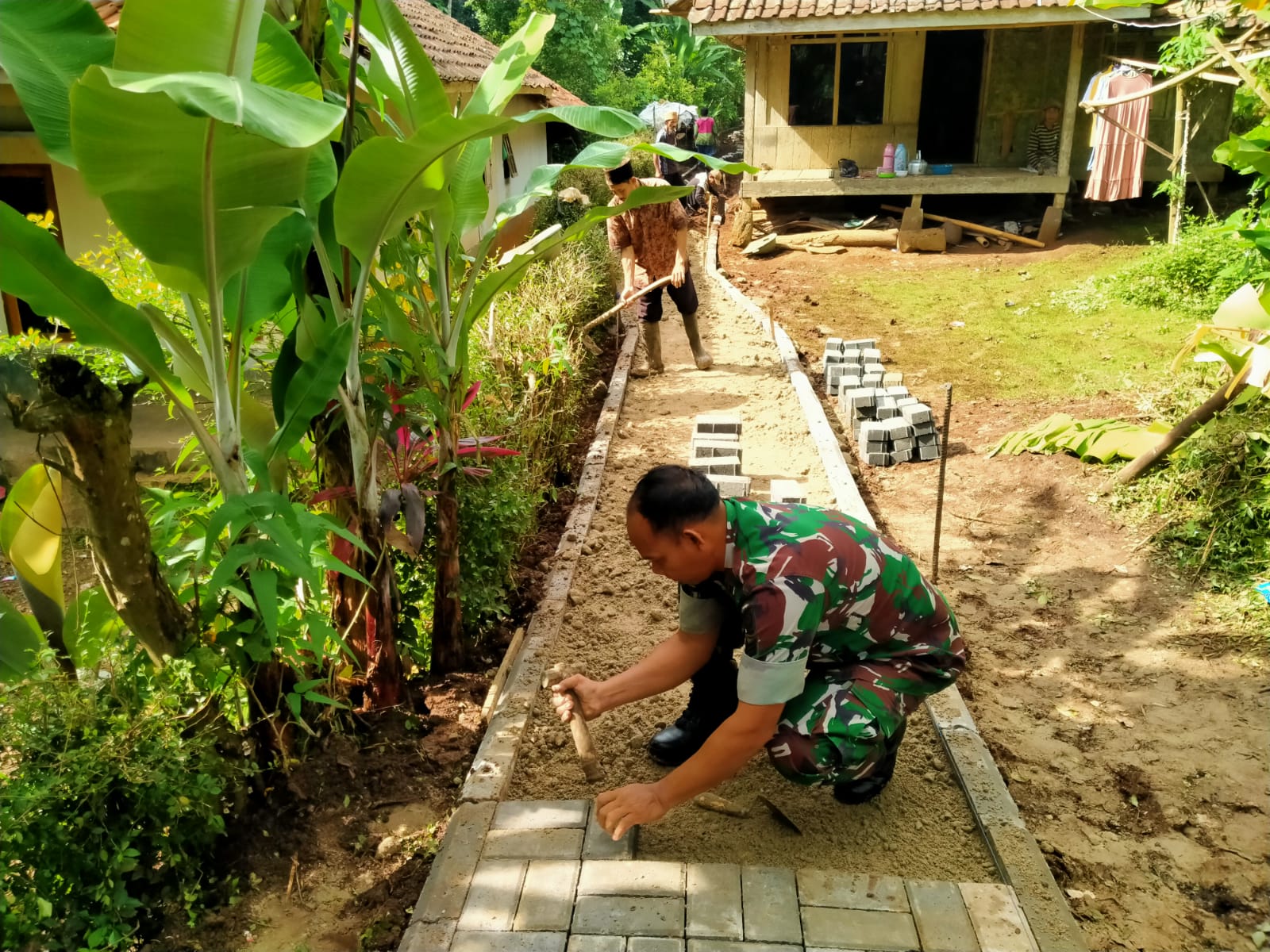 Tumbuhkan Semangat Gotong Royong, Babinsa Koramil 0102/Cadasari Batu Warga Pasang Paving Blok