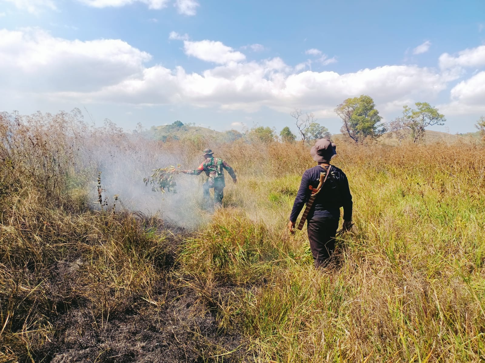 Hutan Terbakar, Babinsa Koramil 01/Lewa dan Bersama Anggota Polhut Padamkan Api Pakai Alat Seadanya