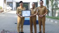 KOTA CIMAHI – Pemerintah Kota Cimahi mencatat peningkatan capaian Reformasi Birokrasi (RB) pada 2025. Berdasarkan hasil evaluasi internal, Indeks Reformasi Birokrasi Kota Cimahi mencapai 89,64 dengan predikat A-, naik 3,35 poin dibandingkan tahun sebelumnya yang berada di angka 86,29. Capaian tersebut menempatkan Kota Cimahi di peringkat ketujuh dari 27 kabupaten/kota di Jawa Barat. Hasil evaluasi tersebut diumumkan bersamaan dengan penyerahan sertifikat evaluasi internal Reformasi Birokrasi kepada perangkat daerah dalam apel pagi yang dipimpin Wali Kota Cimahi, Ngatiyana, Senin (6/7/2026). Kegiatan itu dihadiri Wakil Wali Kota Adhitia Yudisthira, Sekretaris Daerah, para asisten, staf ahli, kepala perangkat daerah, serta aparatur sipil negara (ASN) di lingkungan Pemerintah Kota Cimahi. Dalam amanatnya, Ngatiyana menyampaikan apresiasi kepada seluruh perangkat daerah dan Tim Reformasi Birokrasi yang dinilai telah berkontribusi terhadap peningkatan indeks RB. Menurutnya, capaian tersebut menjadi indikator bahwa upaya membangun birokrasi yang bersih, akuntabel, efektif, adaptif, dan berorientasi pada pelayanan publik mulai menunjukkan hasil positif. "Saya ucapkan terima kasih atas kontribusi dan kerja sama seluruh perangkat daerah serta Tim Reformasi Birokrasi. Peningkatan nilai ini menunjukkan komitmen kuat Pemerintah Kota Cimahi dalam menghadirkan birokrasi yang mampu memberikan pelayanan publik yang semakin berkualitas dan berdampak bagi masyarakat," ujar Ngatiyana. Berdasarkan hasil evaluasi, Dinas Komunikasi dan Informatika Kota Cimahi menjadi perangkat daerah dengan nilai Reformasi Birokrasi tertinggi, yakni 91,61 dengan predikat AA. Posisi berikutnya ditempati Dinas Penanaman Modal dan Pelayanan Terpadu Satu Pintu (87,97), Badan Kepegawaian dan Pengembangan Sumber Daya Manusia Daerah (87,76), Dinas Pekerjaan Umum dan Penataan Ruang (87,53), serta Kecamatan Cimahi Selatan (87,23). Di sisi lain, Pemerintah Kota Cimahi menegaskan bahwa evaluasi Reformasi Birokrasi bukan sekadar penilaian administratif atau ajang pemeringkatan antarsatuan kerja. Evaluasi tersebut menjadi instrumen untuk mengukur efektivitas pelaksanaan program, memastikan penggunaan anggaran selaras dengan hasil yang dicapai, sekaligus mengidentifikasi area yang masih memerlukan perbaikan. Pelaksanaan evaluasi mengacu pada Peraturan Menteri PANRB Nomor 9 Tahun 2023 dengan fokus pada dua aspek utama, yakni manajemen perubahan yang mencakup transformasi pola pikir dan budaya kerja aparatur, serta penataan tata laksana pemerintahan agar lebih efisien, transparan, dan akuntabel. Proses evaluasi dilakukan melalui beberapa tahapan, mulai dari penilaian mandiri oleh perangkat daerah, reviu dan verifikasi data oleh Inspektorat atau asesor internal, hingga penyusunan rekomendasi sebagai dasar perbaikan berkelanjutan pada tahun berikutnya. Melalui evaluasi tersebut, Pemerintah Kota Cimahi berharap reformasi birokrasi tidak hanya meningkatkan capaian indeks, tetapi juga menghadirkan perubahan nyata yang dirasakan masyarakat melalui pelayanan publik yang lebih cepat, transparan, dan berkualitas. Ke depan, hasil evaluasi ini akan menjadi pijakan dalam memperkuat tata kelola pemerintahan sekaligus mempertahankan bahkan meningkatkan posisi Kota Cimahi sebagai salah satu daerah dengan kinerja Reformasi Birokrasi terbaik di Jawa Barat.
